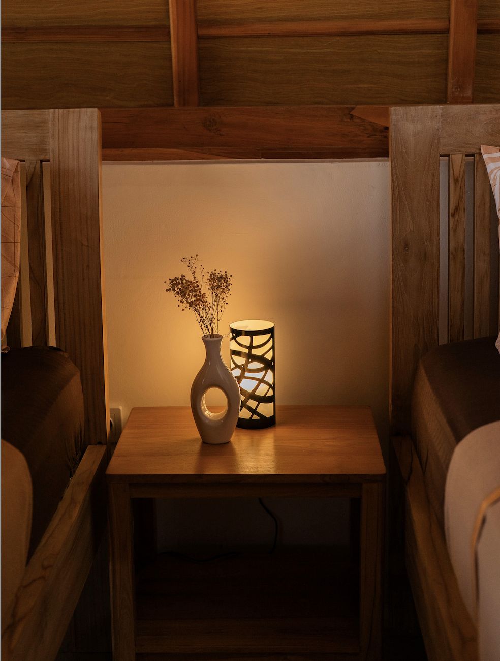 Bedside lamp and vase detail in a wooden bungalow