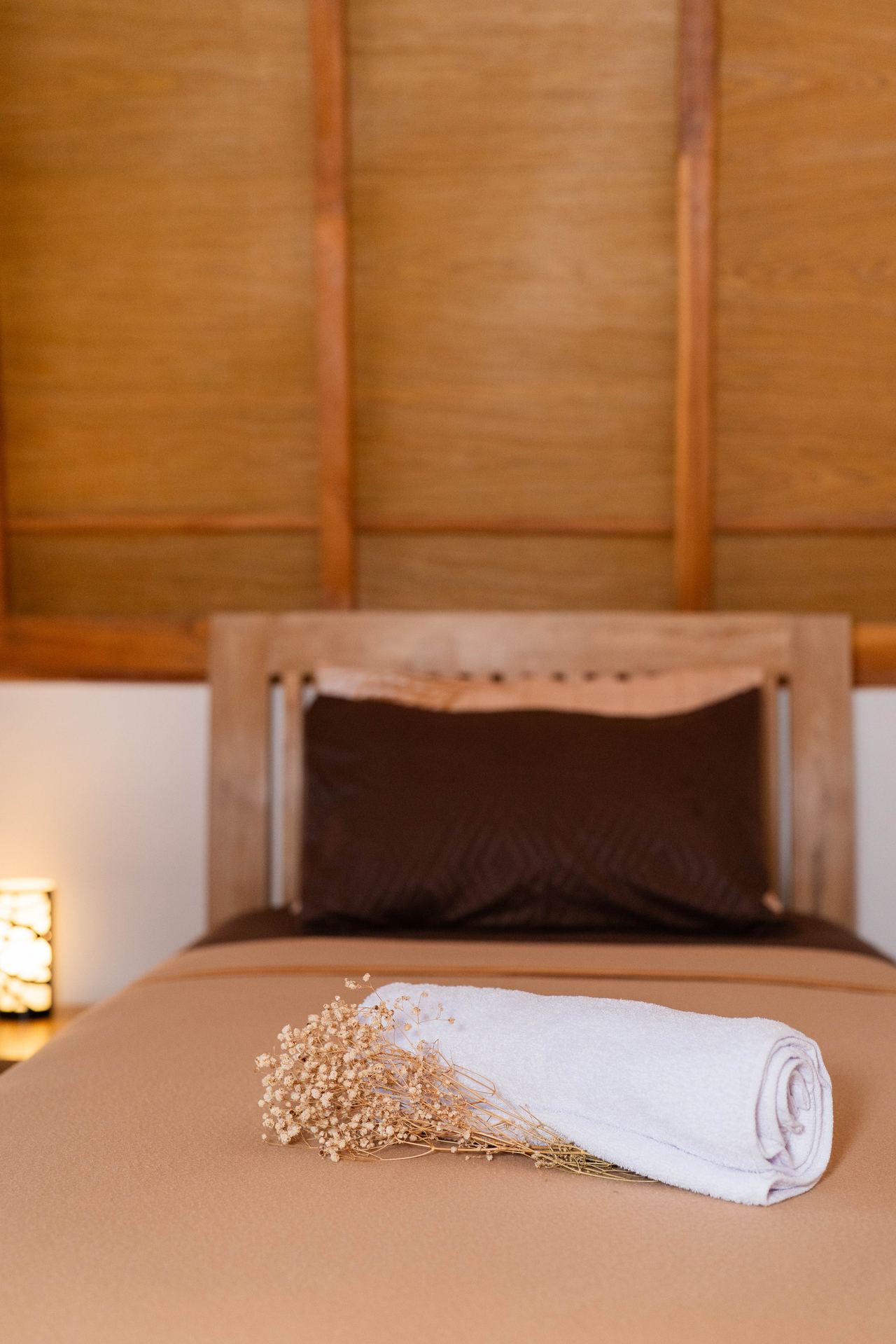 Bed with fresh towel and dried flower decoration